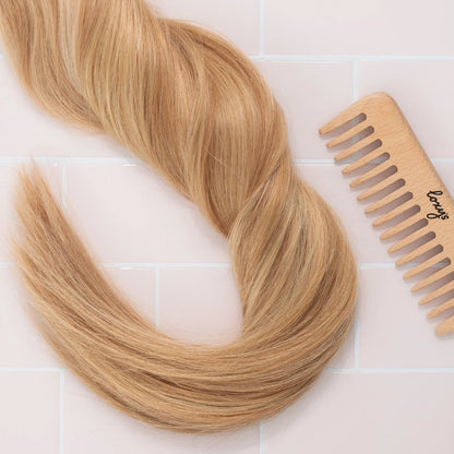 Boho hair extensions with a wooden comb on a light tiled background