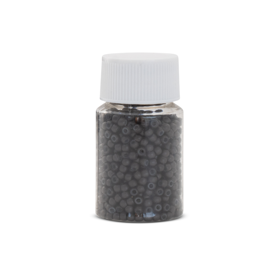 Small jar with a white lid filled with small beads on a white background