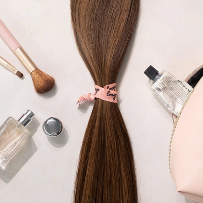 Loxys Java hair extensions on a white background with various beauty products laying around it