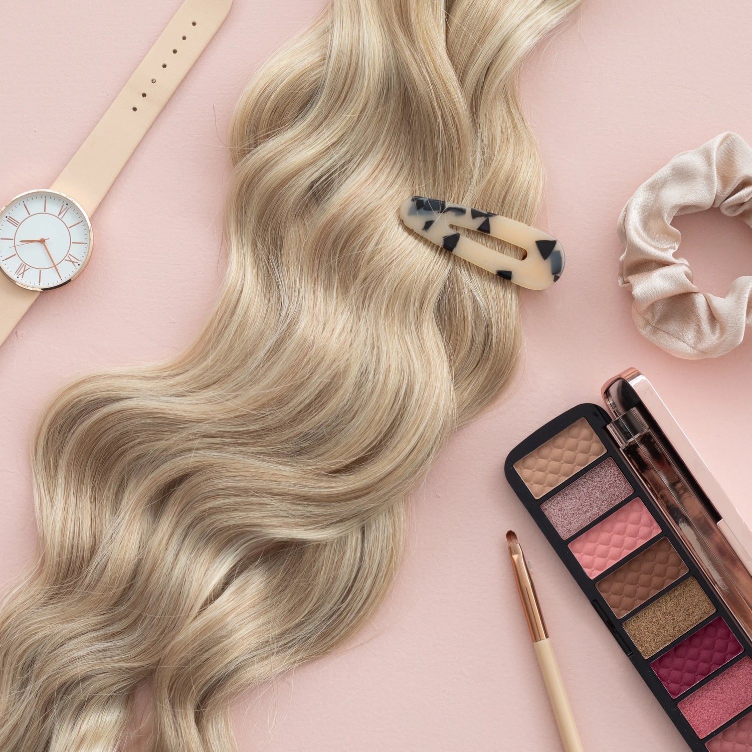 Loxys Pearl Extensions on a pink background with various beauty items like hair clips, scrunchies, and eyeshadow laid around them
