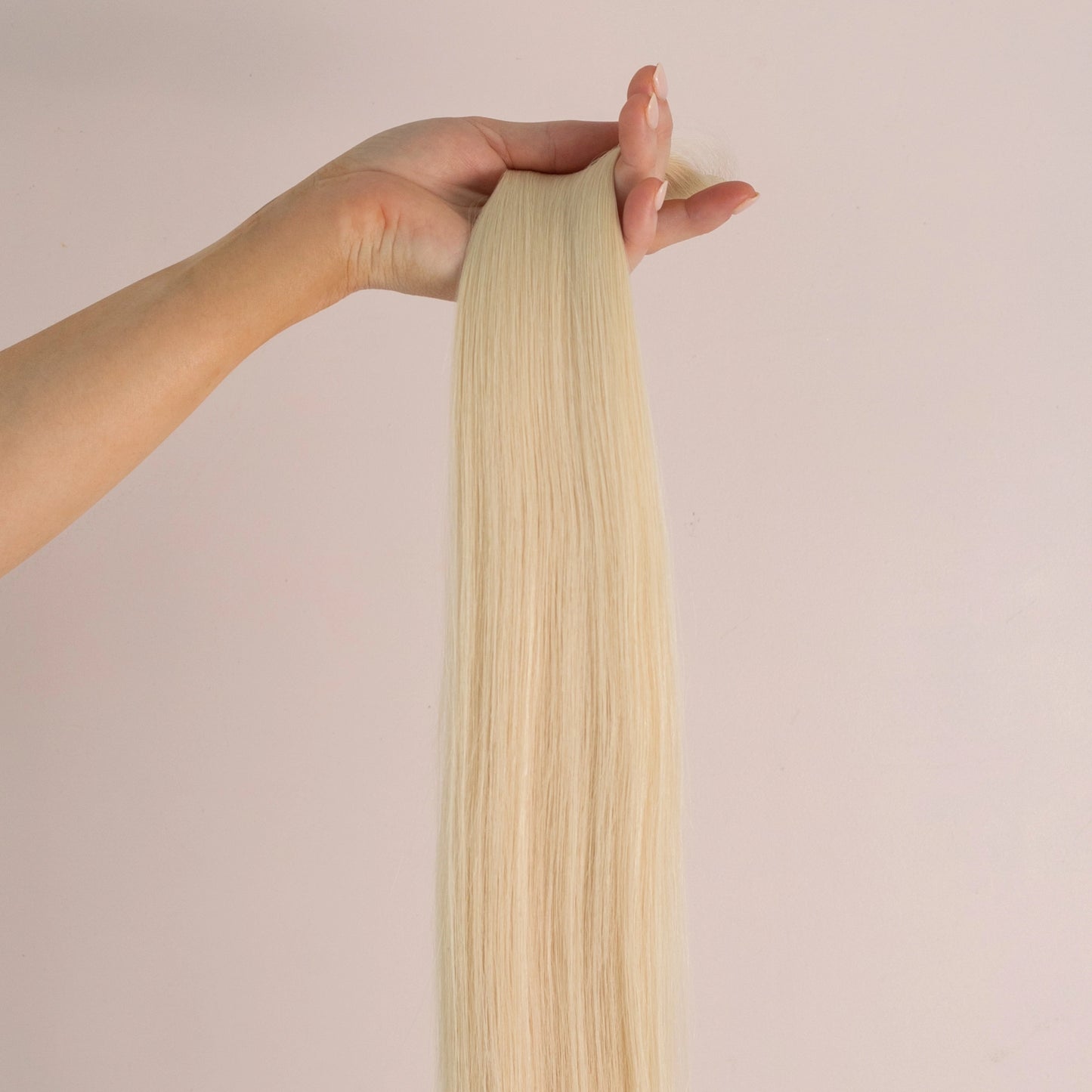 A hand holding up Loxys Blondie weft against a neutral background