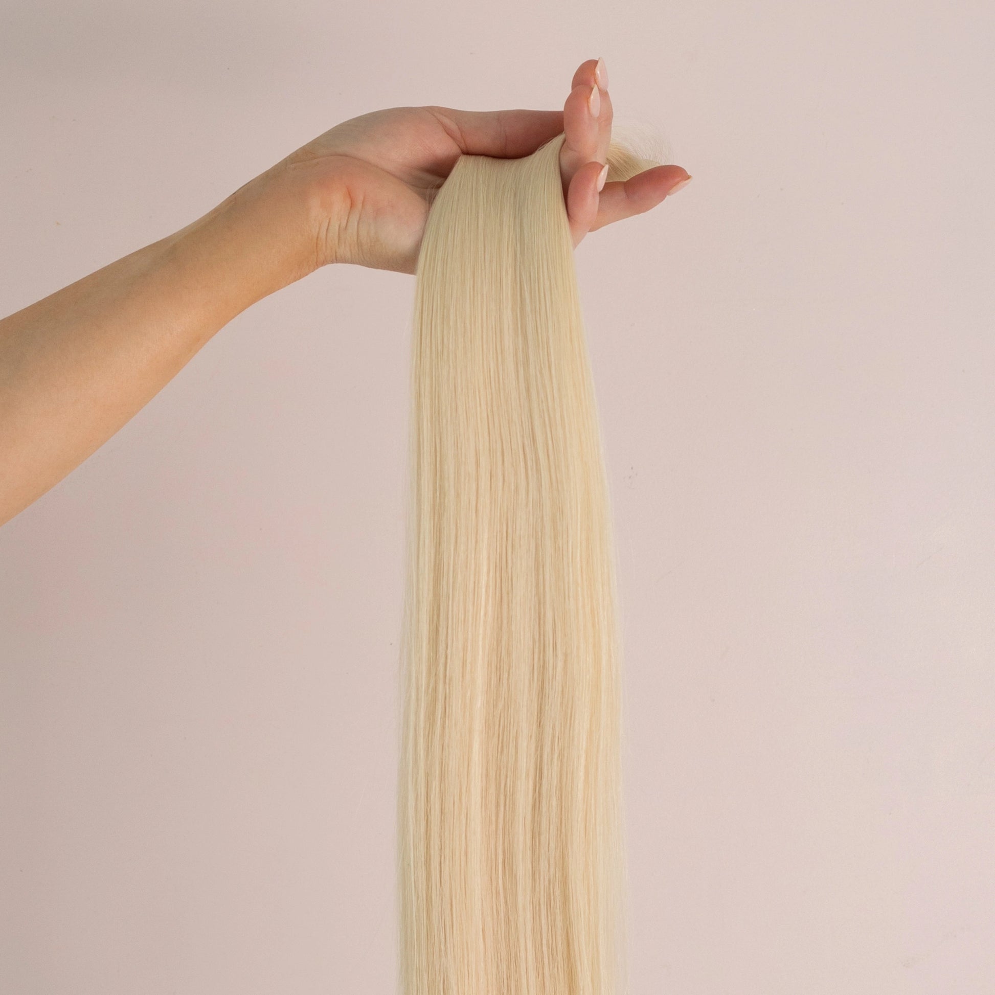 A hand holding up Loxys Blondie weft against a neutral background